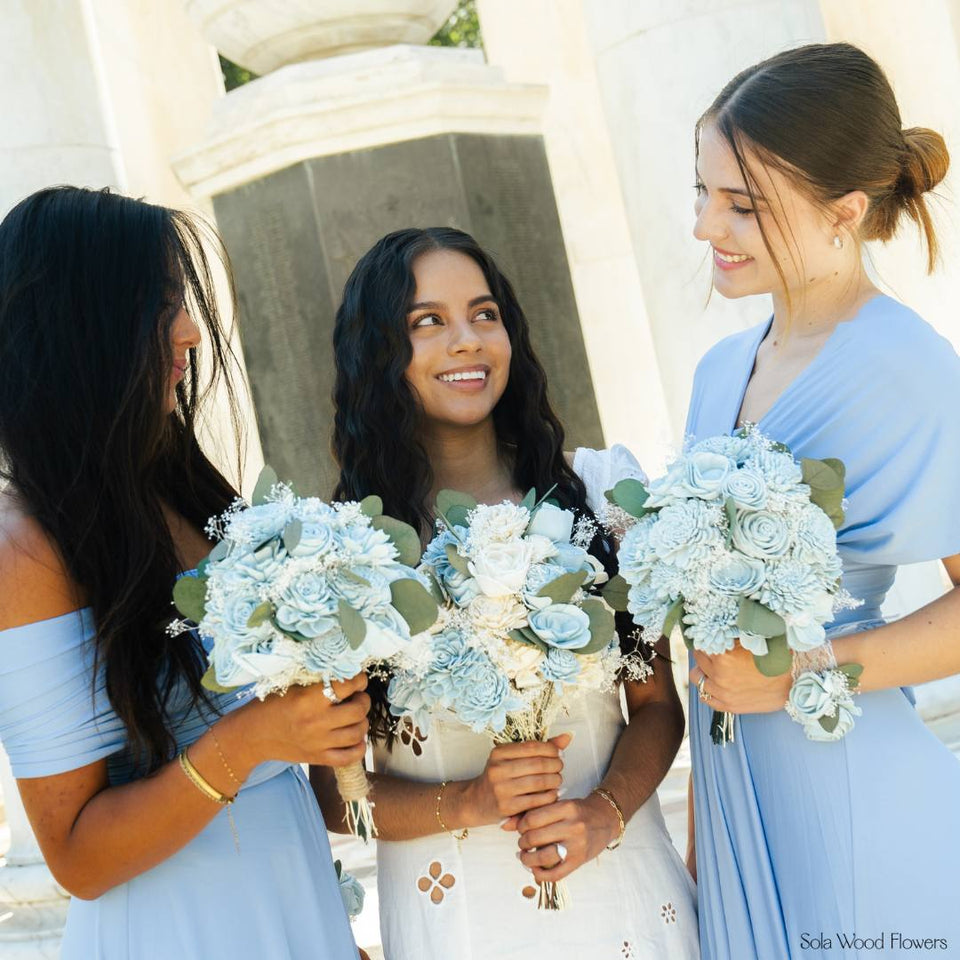 A sampler flower held next to a wedding dress in daylight