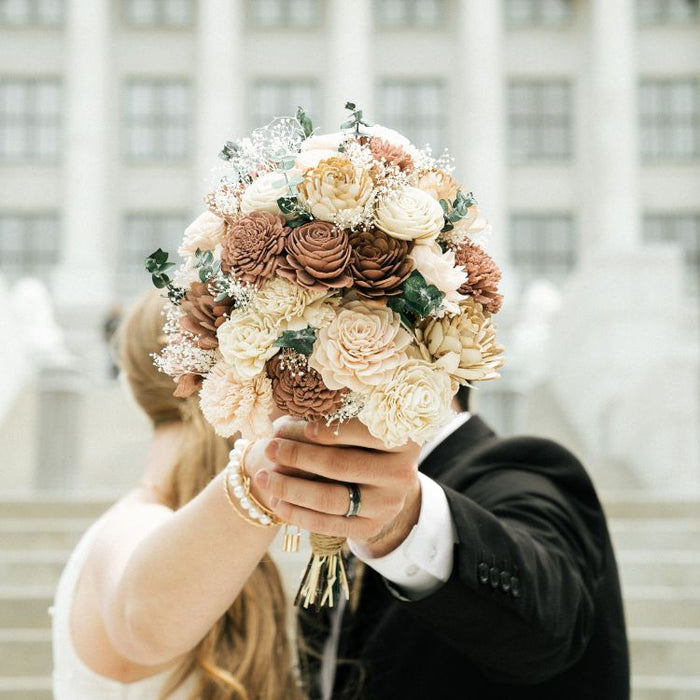 Sola wood wedding bouquet held at the bride's chin height